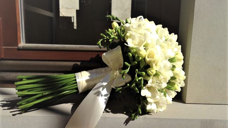 okrúhla svadobná kytic z bielych frézií previazaná bielou stuhou a mašličkou